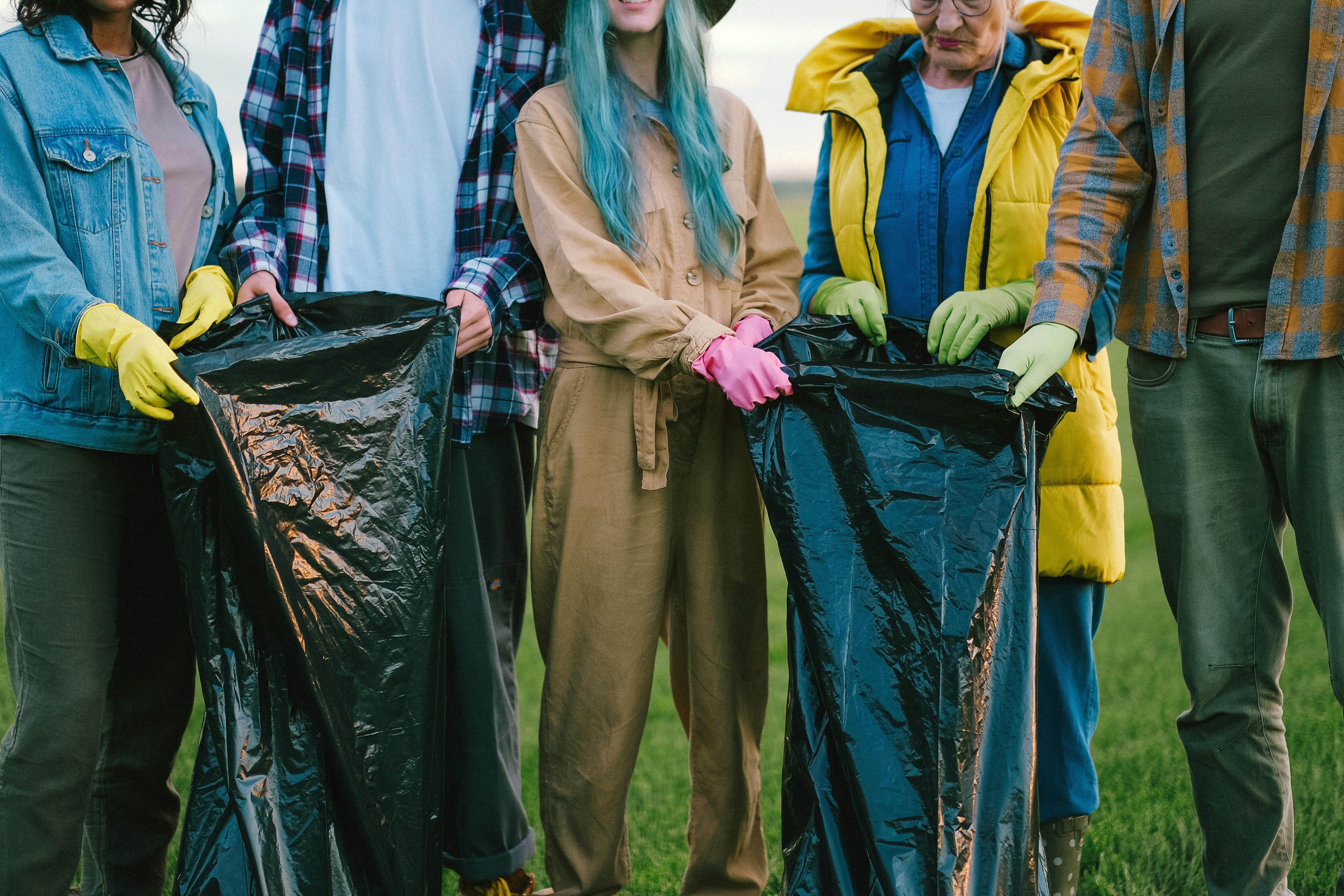 People Standing on Green Grass Field while Holding Plastic Bags - Photo by Anna Shvets
